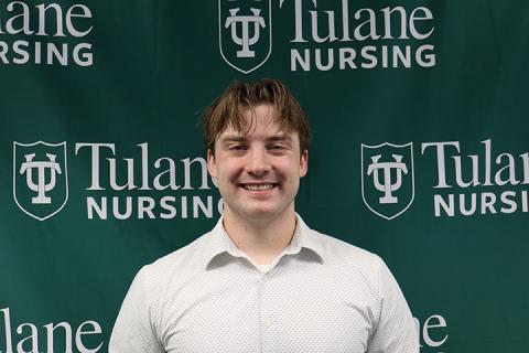 Smiling young man in a light shirt against a green Tulane Nursing background.