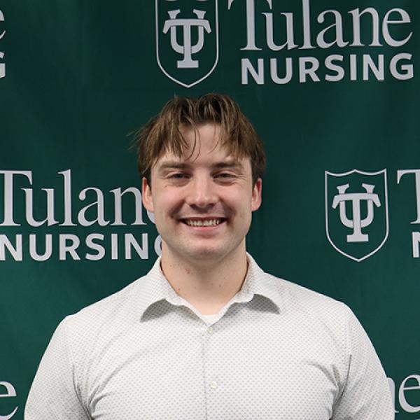 Smiling young man in a light shirt against a green Tulane Nursing background.